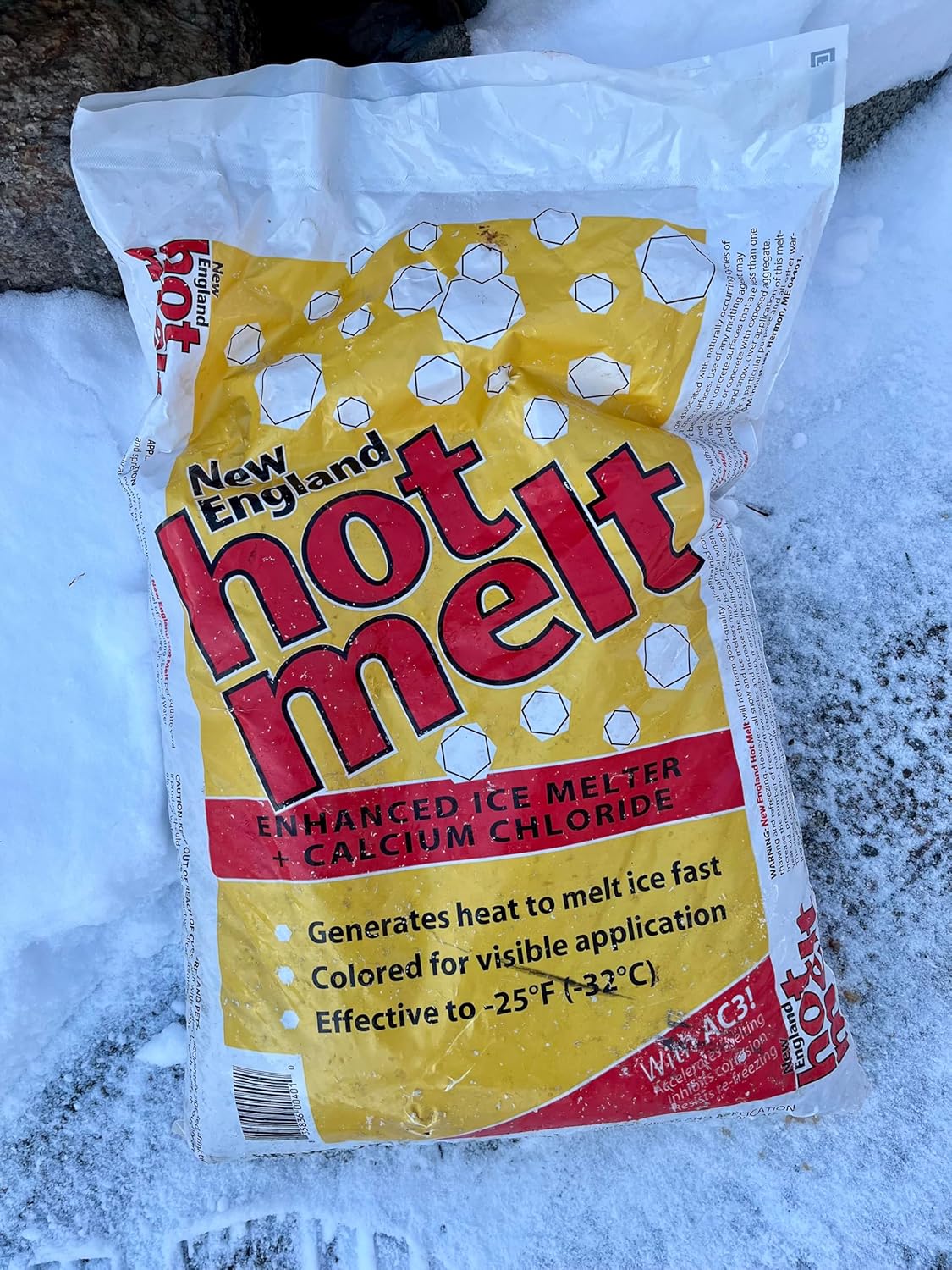 Bag of New England Hot Melt ice melter on a snowy ground